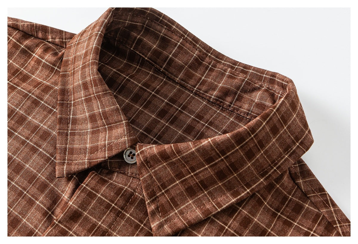 Close-up of a brown windowpane-check shirt collar with a dark button.