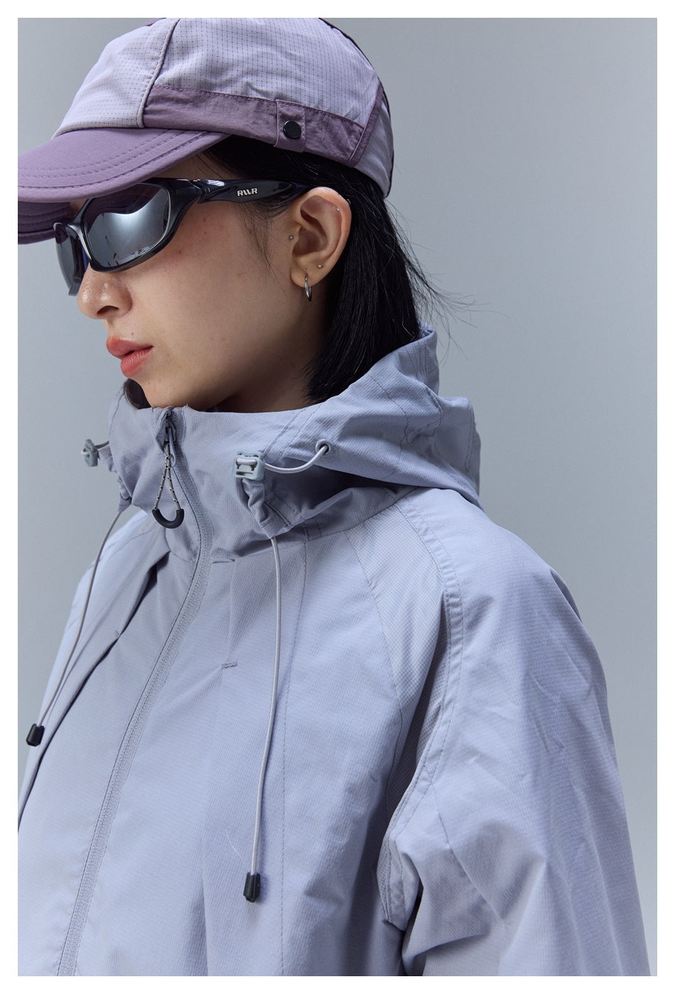 Close-up of a model wearing a light gray hooded jacket with an adjustable drawcord collar.