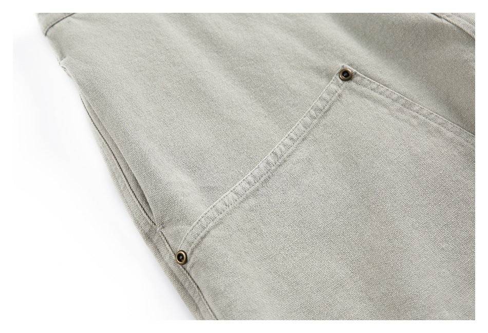 Close-up of light gray-beige bottoms showing a slanted pocket with stitched edges and metal rivets.