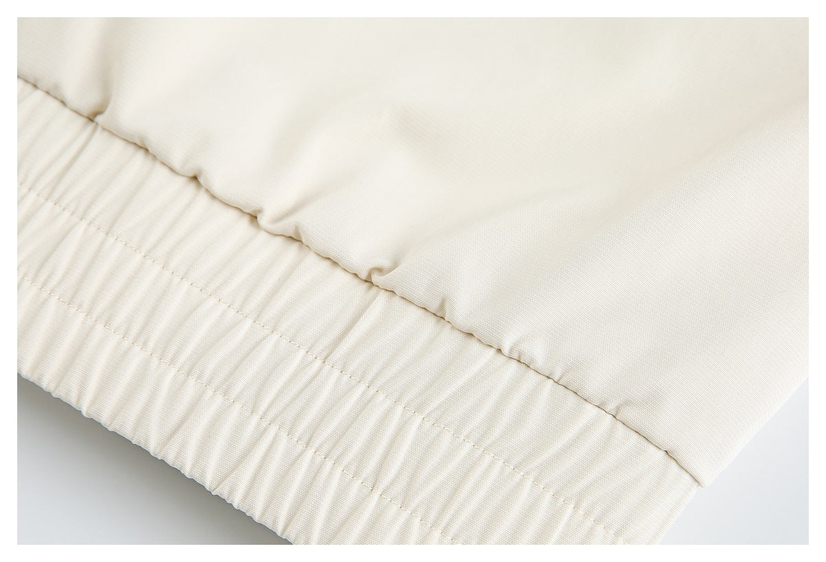 Close-up of the gathered elastic hem on a cream garment.