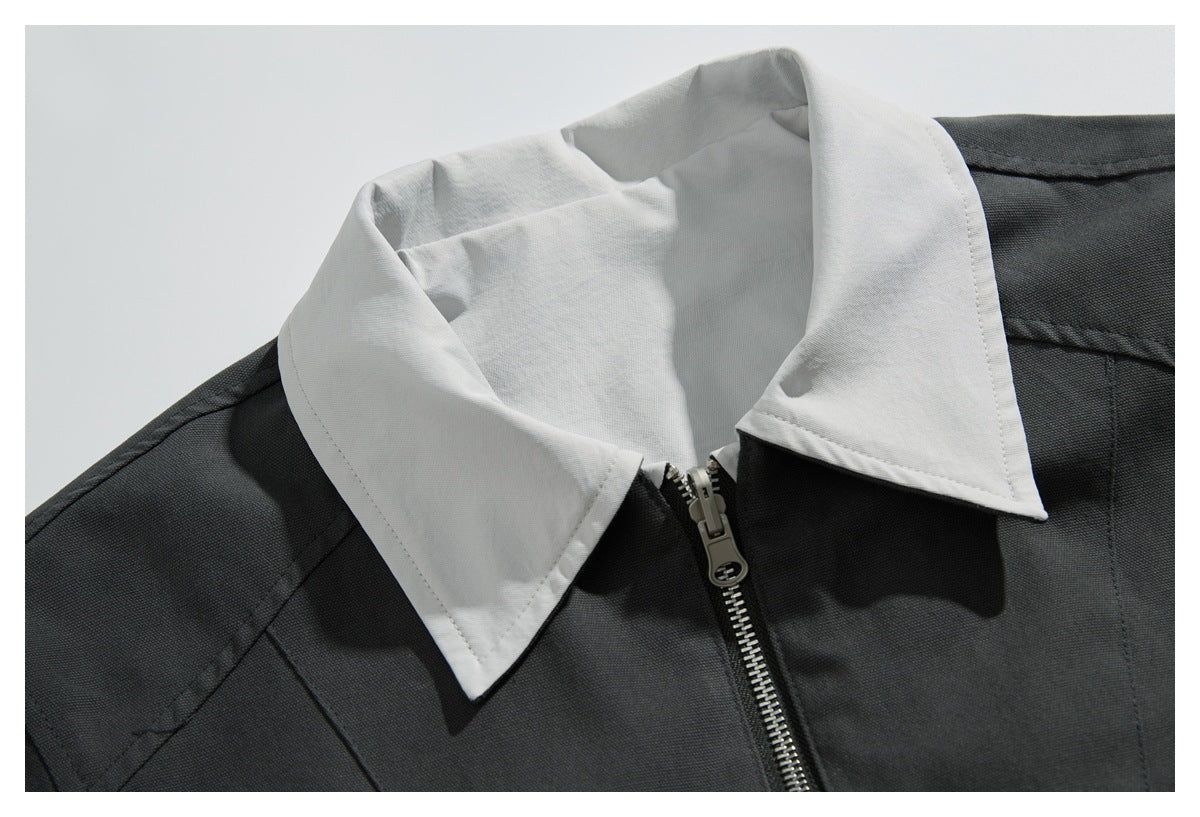 Close-up of a charcoal jacket's contrasting white pointed collar and front zipper.