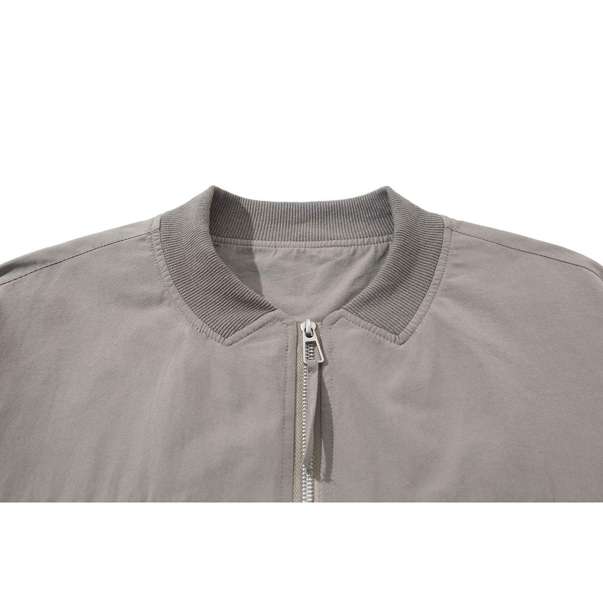 Close-up of a taupe zip jacket showing its ribbed collar, front zipper and stitching.