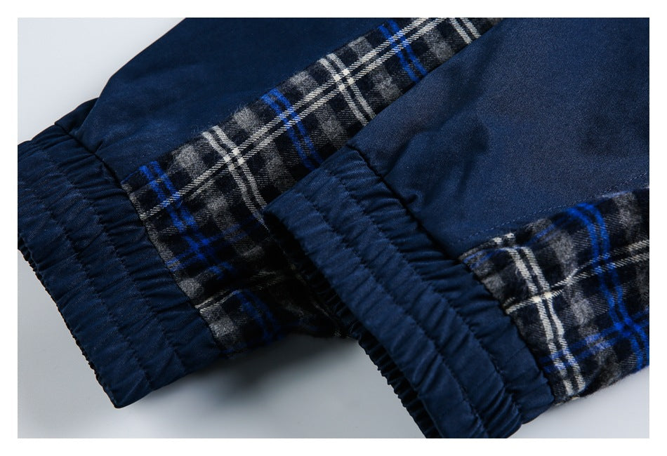 Close-up of navy garment cuffs with gathered seams and gray, white, and blue plaid panels.