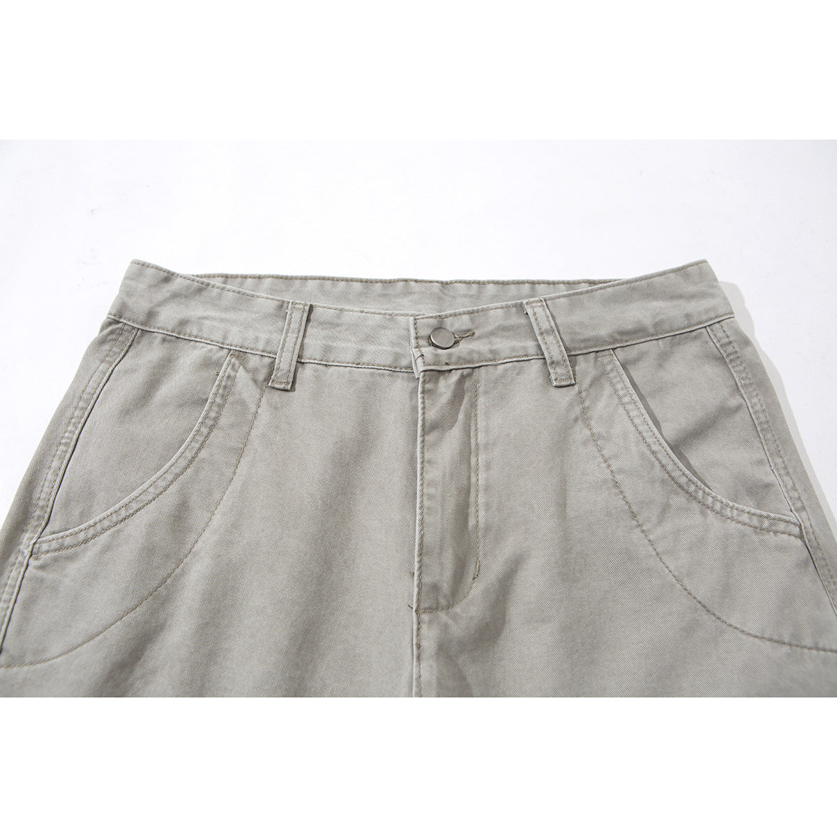 Close-up of light gray pants showing the waistband, button closure, belt loops, and curved front pockets.