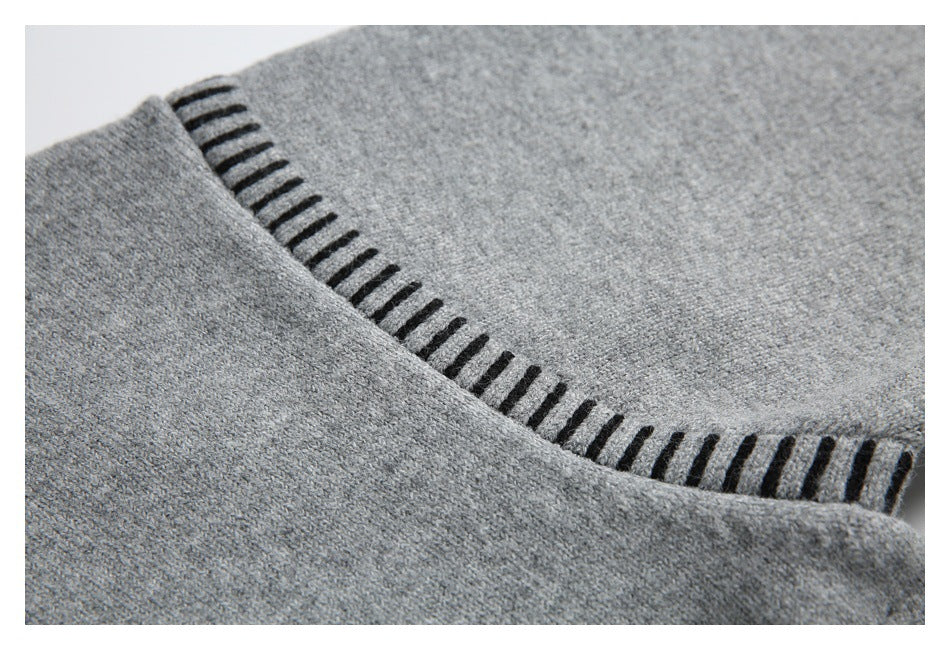 Gray knit sweater detail showing black ladder-like stitching along a curved edge.