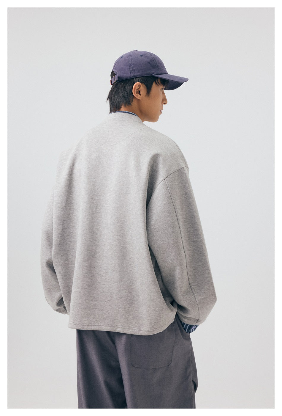 Model wearing the light gray jacket, shown from behind with its plain back visible.