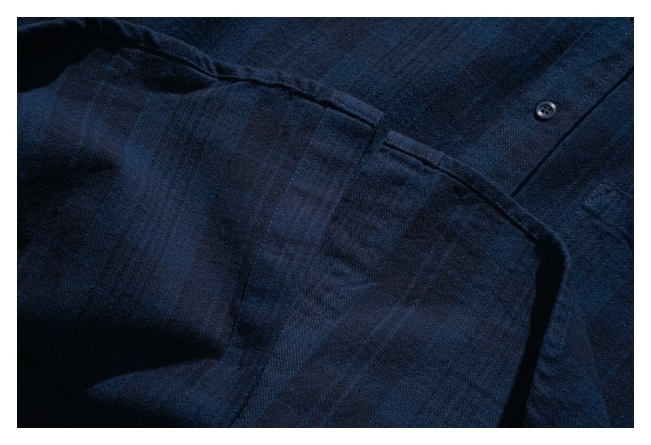 Close-up of a seam and button on the dark navy shirt.