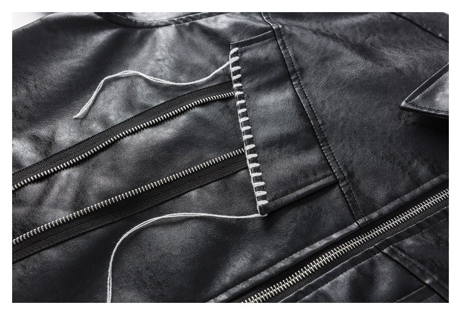 Close-up of the black jacket's zippers, stitched flap, seams, and loose white decorative threads.