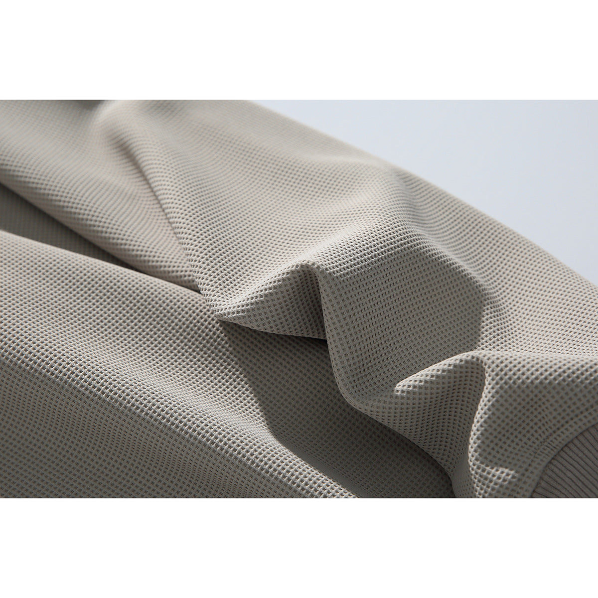 Close-up showing the raised waffle texture of a light gray sweatshirt fabric.