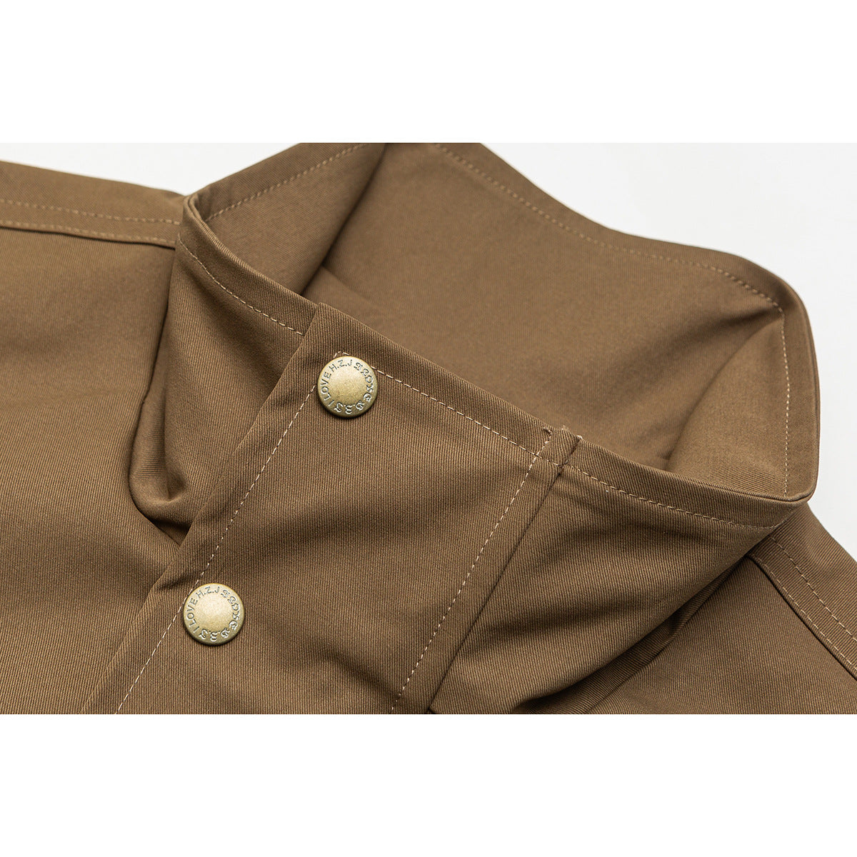 Close-up of a brown jacket collar and placket with two round metal snaps and visible stitching.