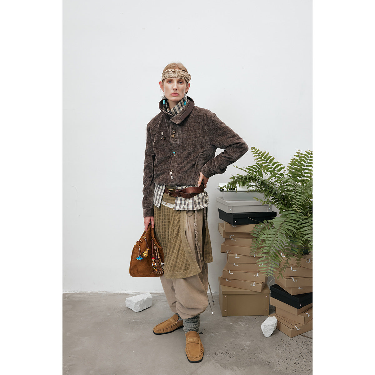 Model wearing a dark brown button-front jacket with a high collar, styled with layered neutral garments.