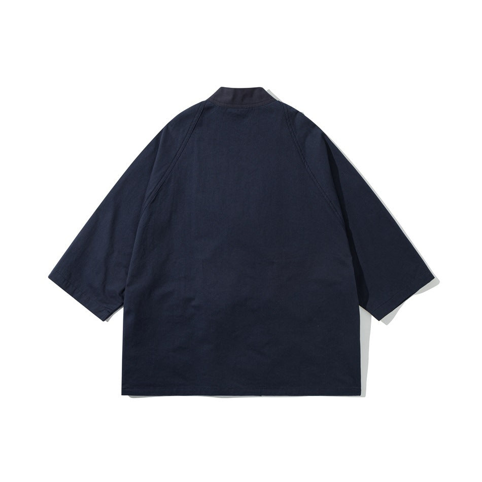 Back view of a loose navy jacket with three-quarter sleeves and a short standing collar.