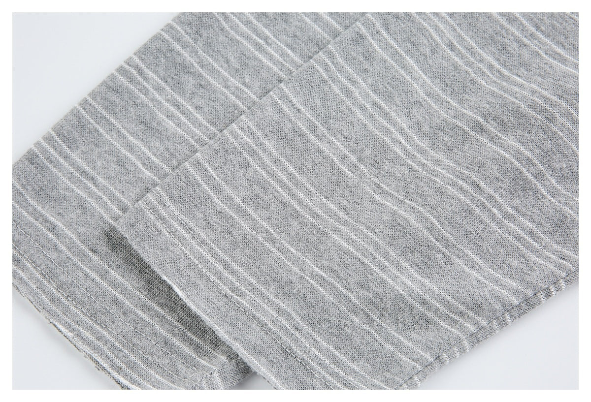 Close-up of overlapping sections and stitched edges on a gray, white-striped knit garment.