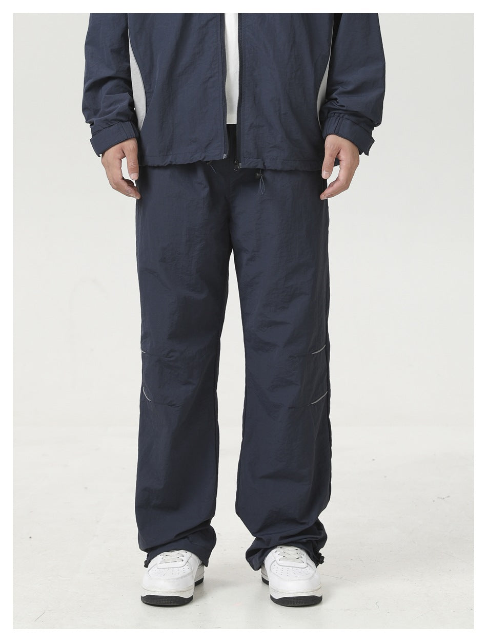 Cropped view of a person wearing navy wide-leg pants with knee stripes, hem toggles and white sneakers