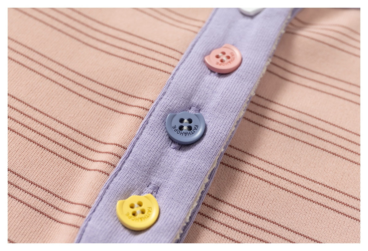 Close-up of a pink striped garment's lavender button placket with pink, blue, and yellow buttons.