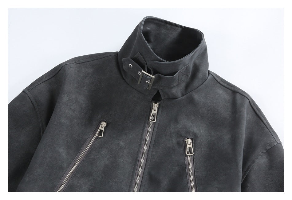 Close-up of a charcoal jacket front with a tall buckled collar and several silver zippers.