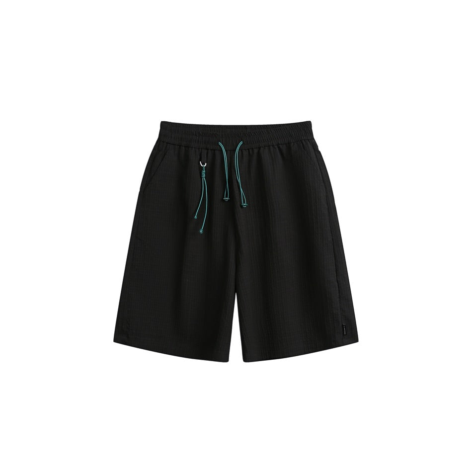 Black shorts shown from the front, with an elastic waistband, turquoise drawcords, and slanted side pockets.