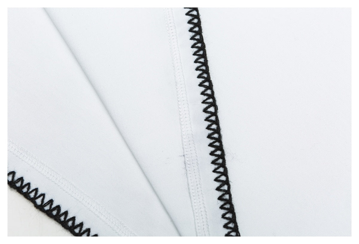 Close-up of white garment construction with interior seams and black loop stitching along the edge.