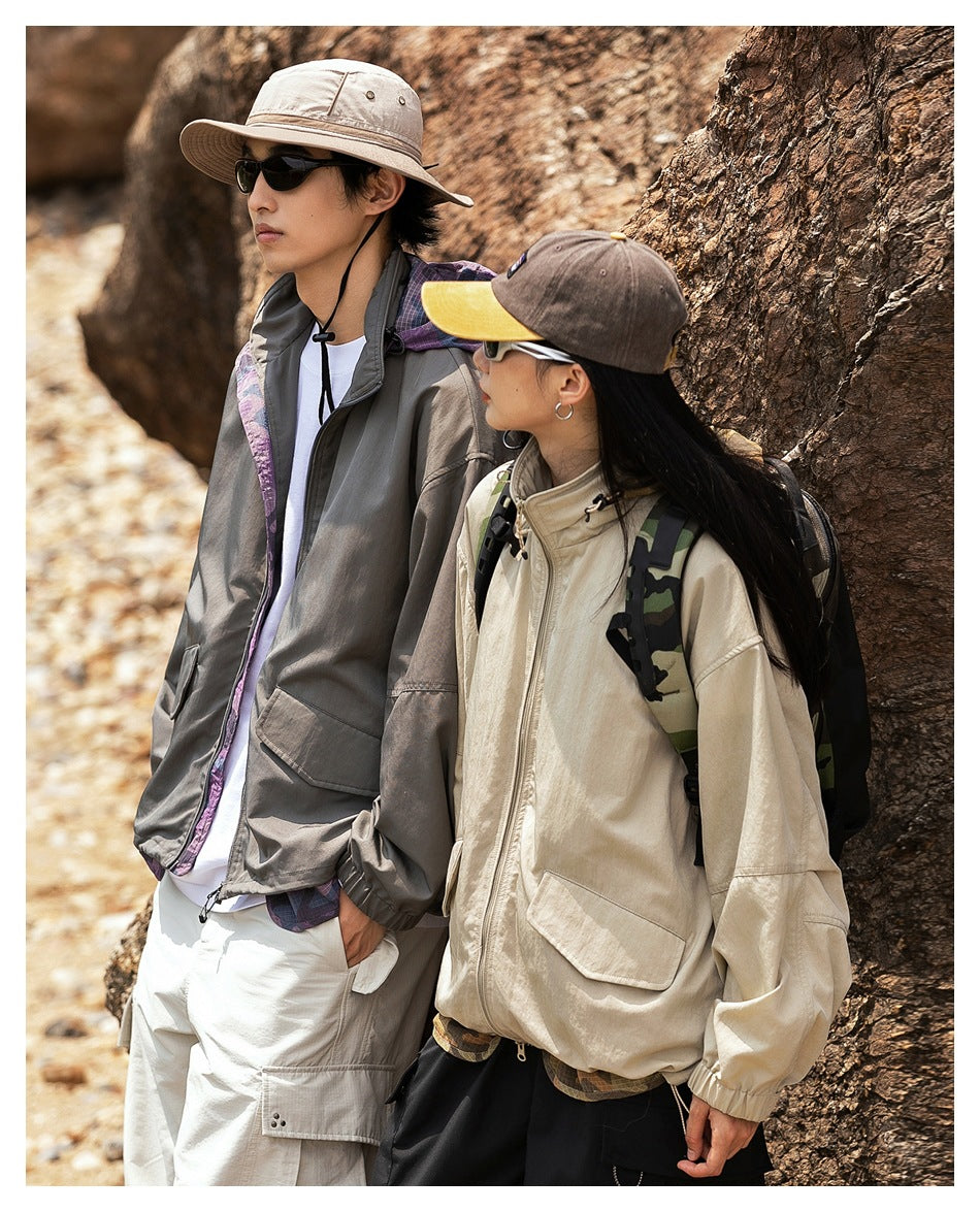 Two hikers stand by a tree wearing oversized jackets; the foreground woman wears a cream jacket with large pockets.
