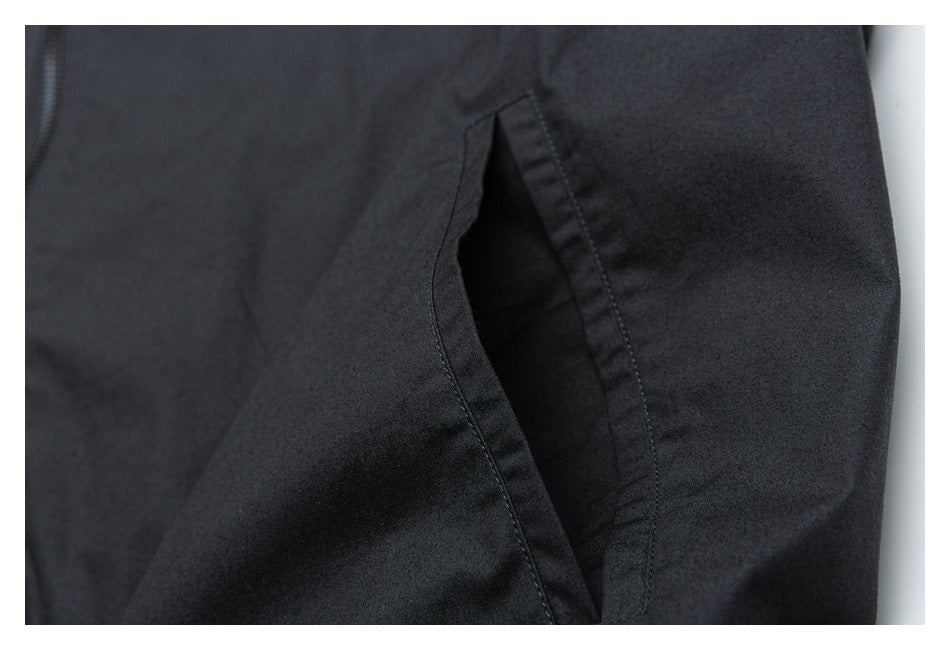 Close-up of a dark garment showing a side pocket opening and stitching.
