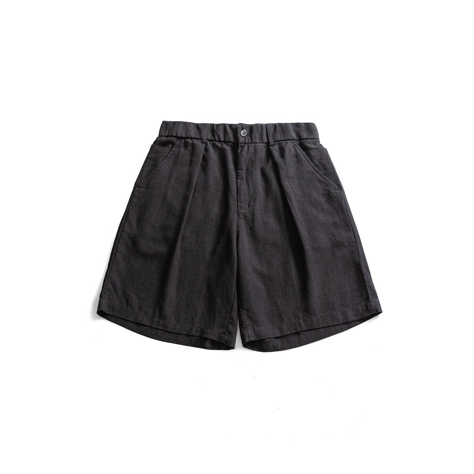 Black pleated knee-length shorts with elastic waistband and button closure, flat lay front view