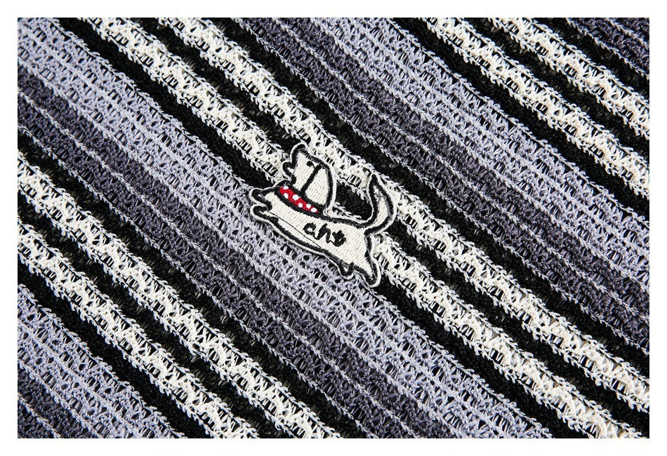 Close-up of a small embroidered cowboy-hat patch on black, charcoal, and ivory striped open-knit fabric.