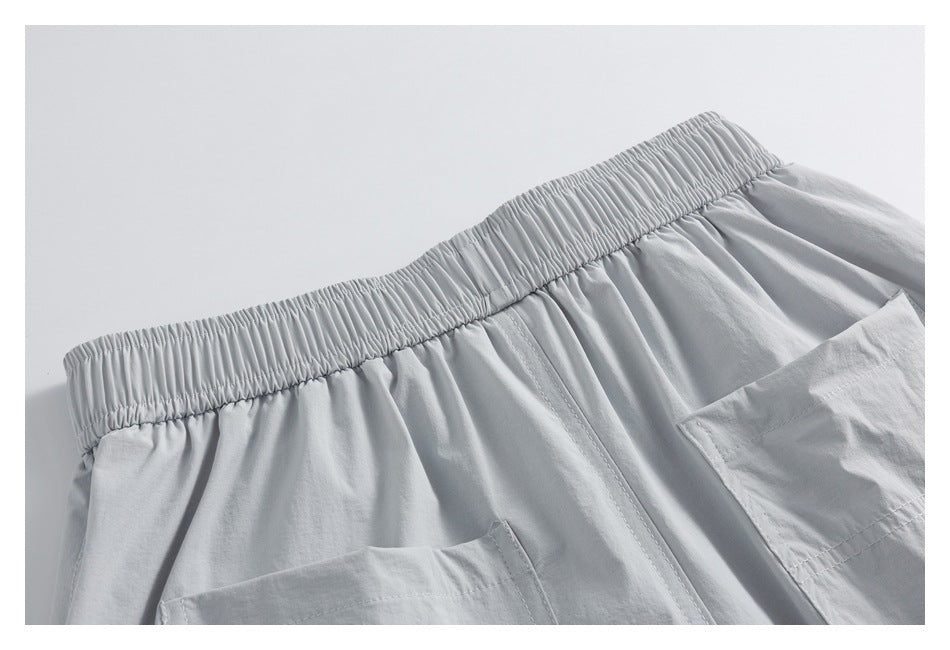 Close-up of light gray shorts showing the gathered elastic waistband, stitching, and partial pockets.