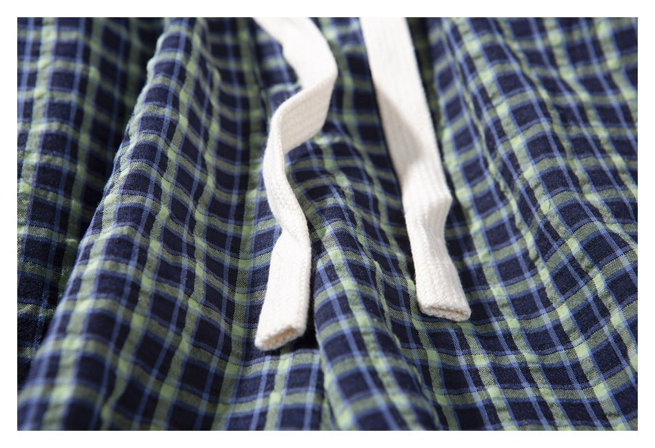 Close-up of the white drawstring against the navy, blue, and green plaid shorts.