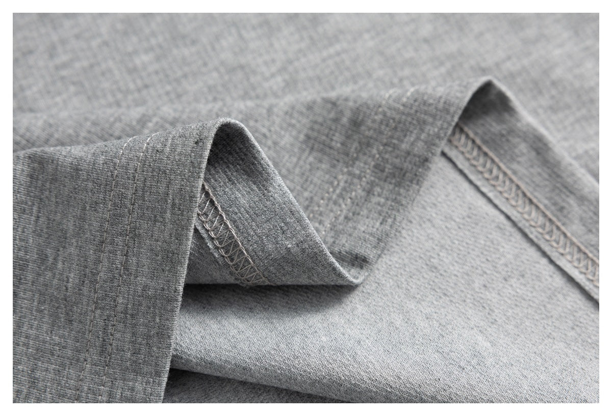 Close-up of gray garment fabric showing the hem stitching and overlocked seam finish.