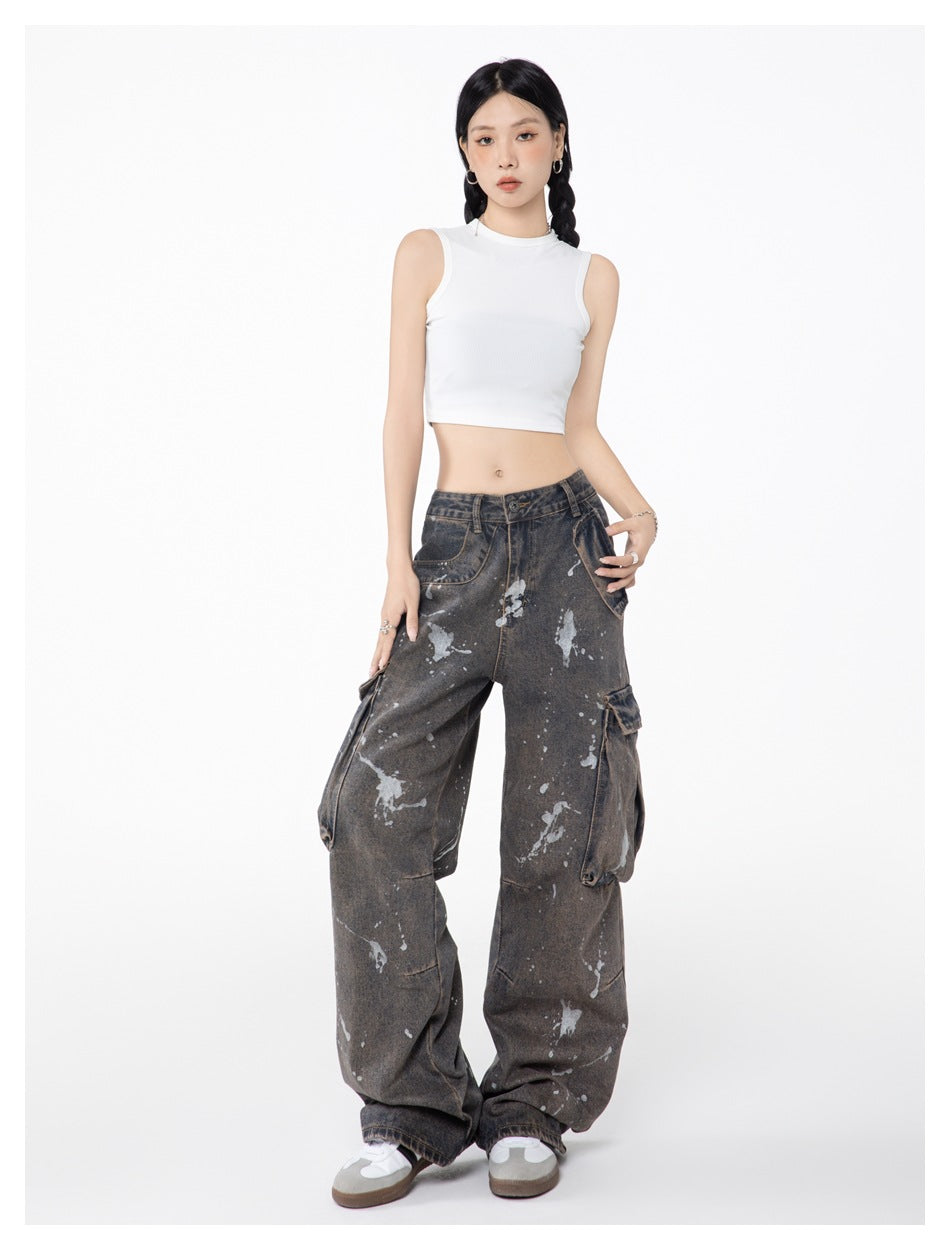 Model posing in faded wide-leg cargo jeans with silver splatter marks and a white cropped tank top