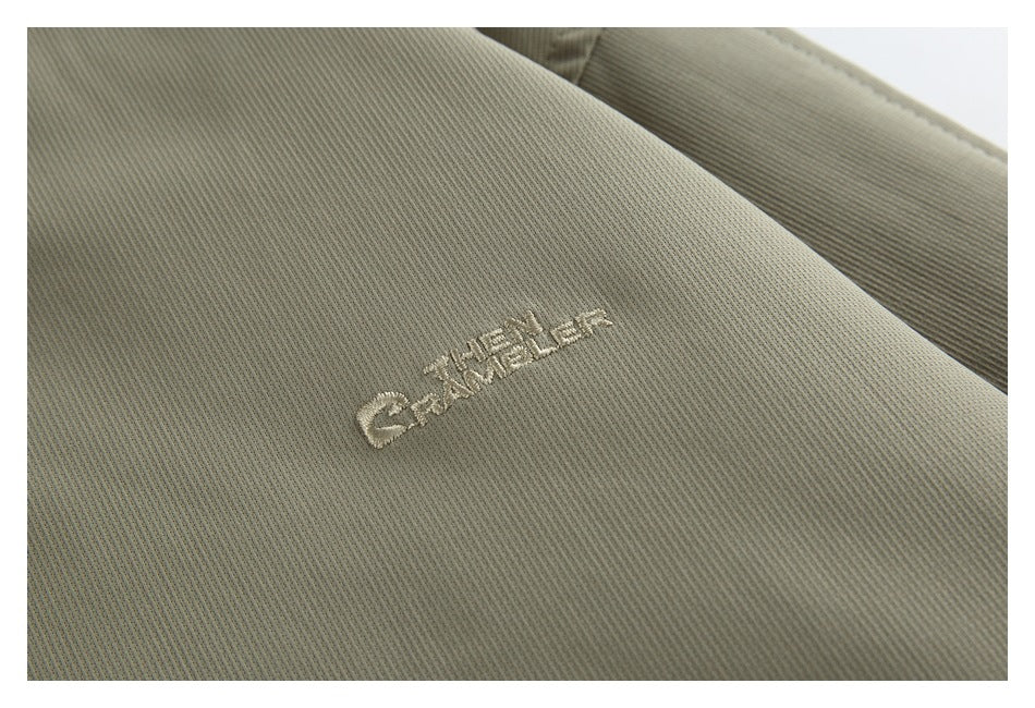 Close-up of light-colored embroidered lettering on the olive-gray jacket.