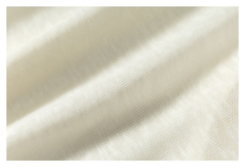 Macro view of the fine knit texture of ivory fabric arranged in soft folds.