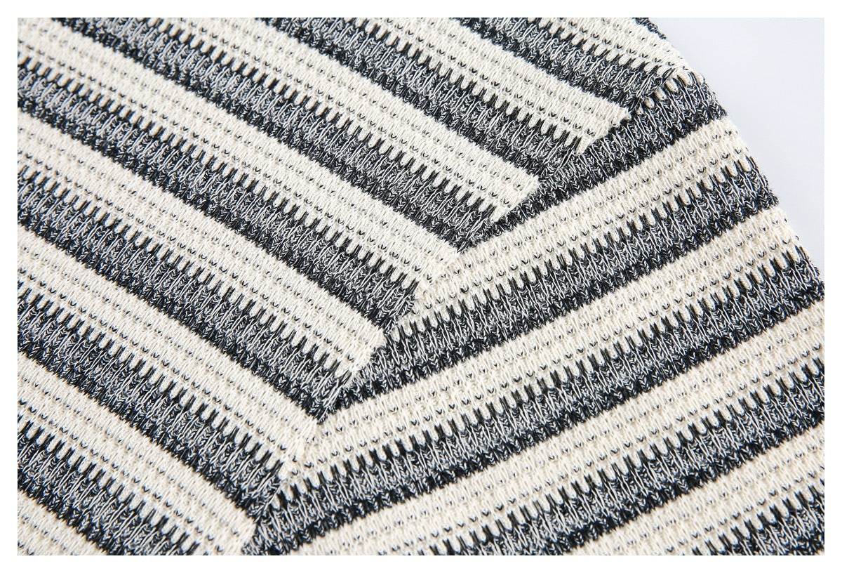 Close-up of the striped knit garment's shoulder seam and textured black-and-ivory fabric.
