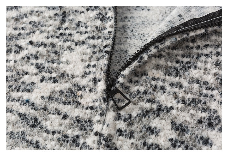 Close-up of a black zipper and pull on a black-and-white fuzzy garment.