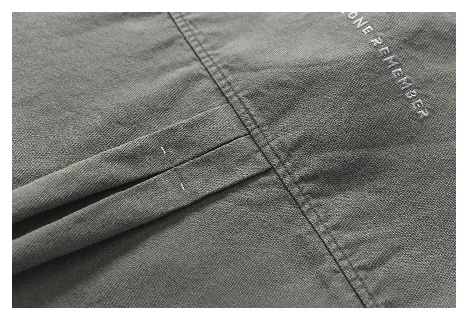 Close-up of gray garment stitching and folds with partial white embroidered English lettering.
