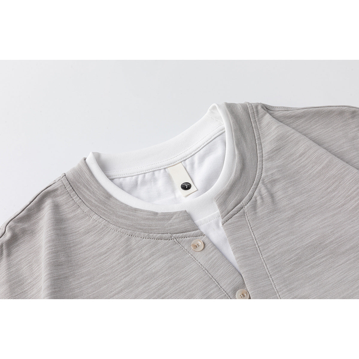 Close-up of a light gray heather Henley shirt neckline with white inner collar and small buttons.