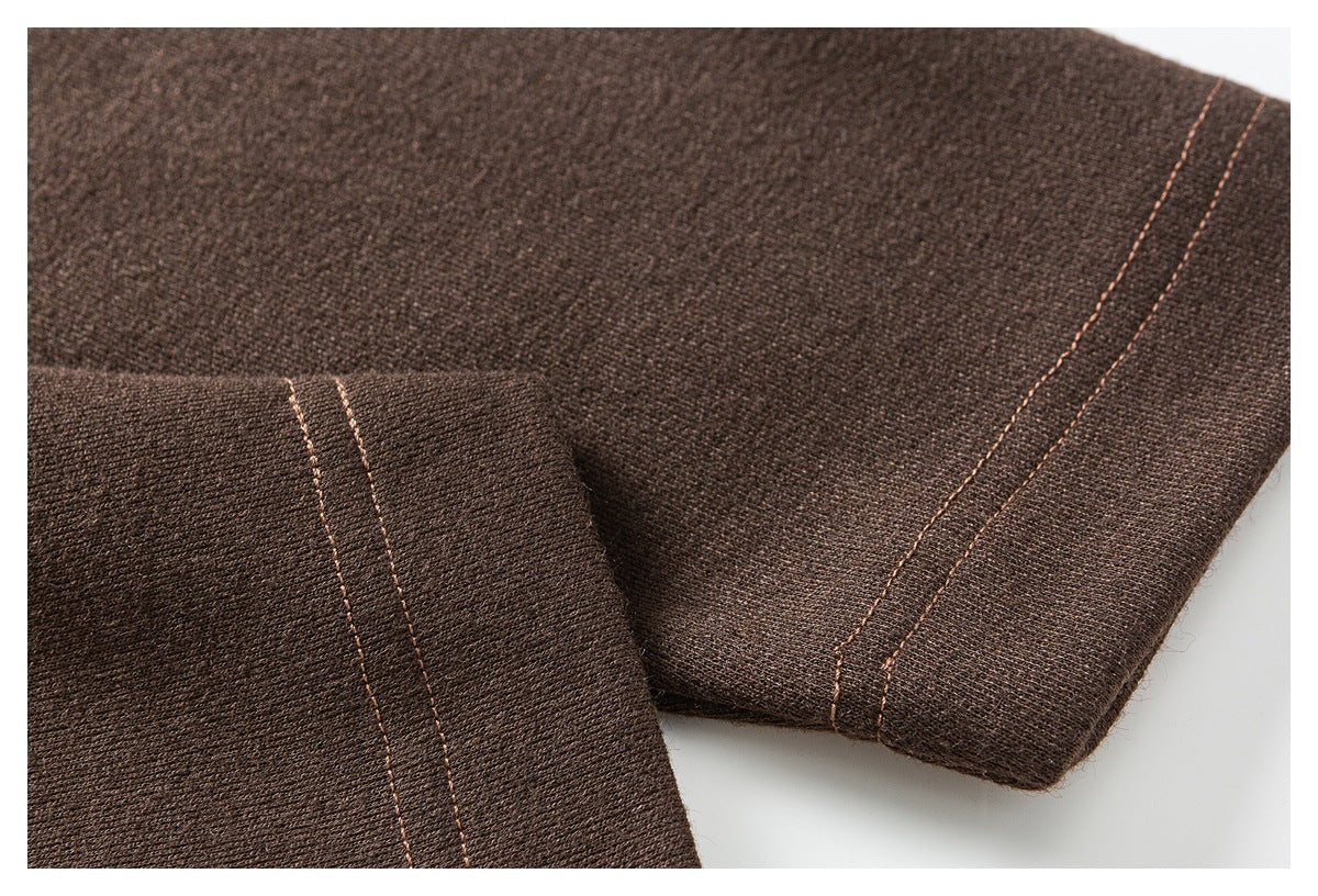 Close-up of dark brown fabric with parallel seam stitching and a folded edge.
