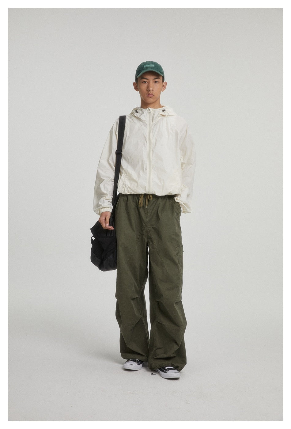 Front-facing model wearing an ivory hooded zip jacket and loose olive cargo pants.
