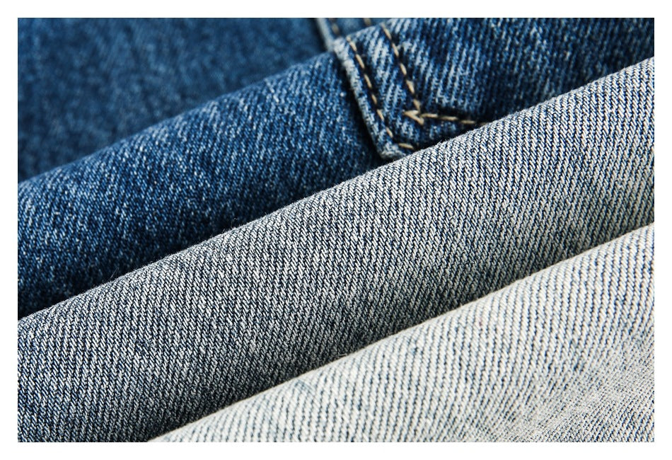 Macro view of layered blue and light-wash denim showing the woven texture and stitching.