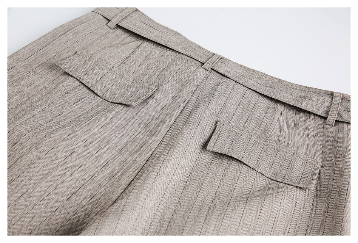 Close-up of the back of taupe-gray herringbone trousers with belt loops and two welt pockets with flaps.