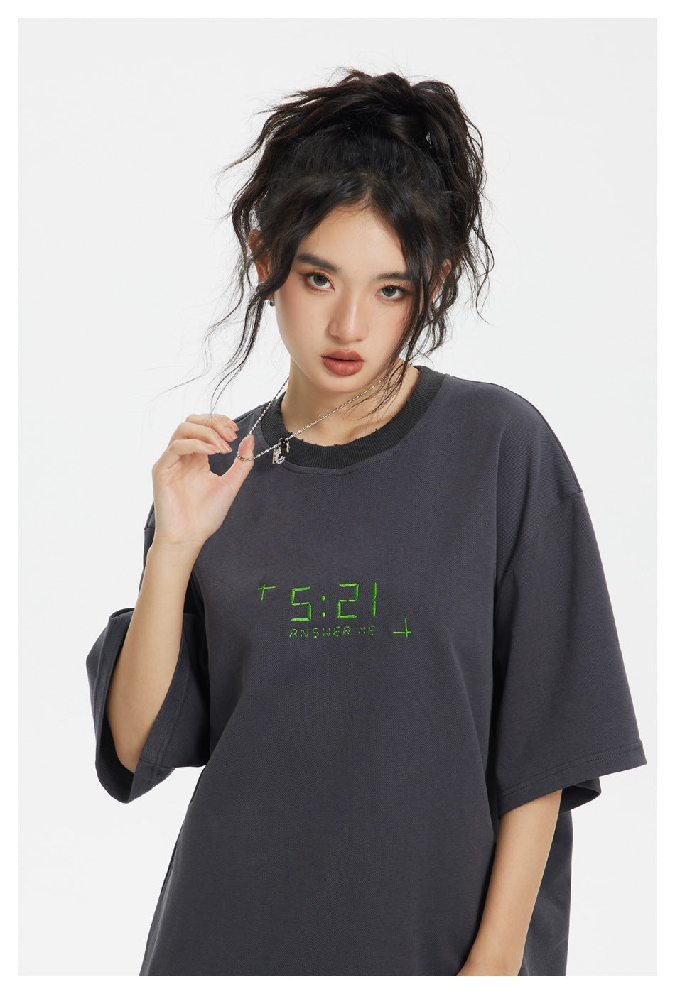 Close view of a model wearing a charcoal T-shirt with green chest lettering and a ribbed dark collar.