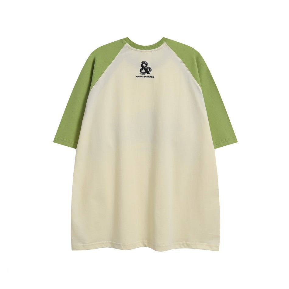 Front view of an ivory raglan T-shirt with light green sleeves and a small black chest emblem.