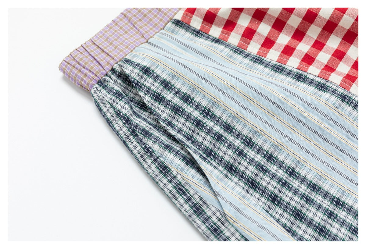 Close-up of a multicolored garment with red gingham, lavender checks, pale blue stripes, and dark green plaid panels.