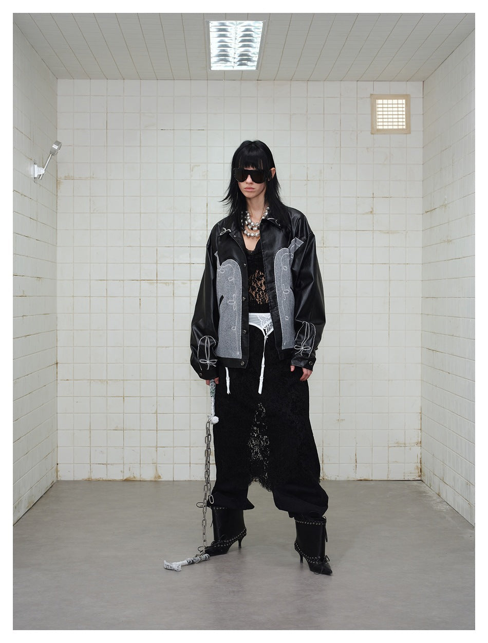 Full-length model wearing a black and gray embroidered jacket with a black lace skirt and boots.