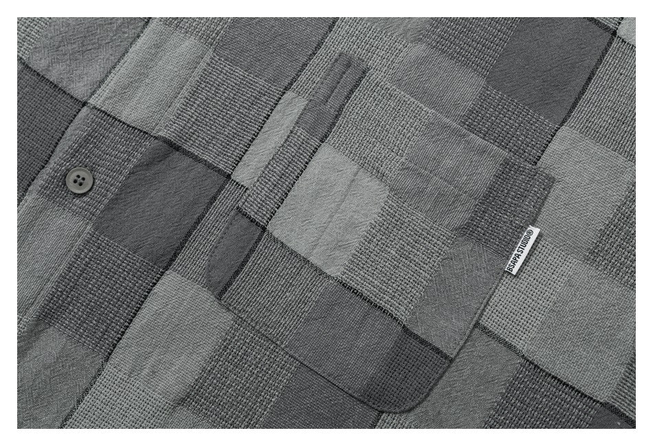 Close-up of a gray patchwork-check shirt pocket, button, and small woven label.