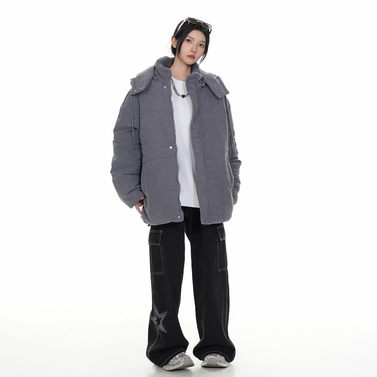 Full-length model wearing an open charcoal-gray padded jacket with shoulder flaps over a white top.