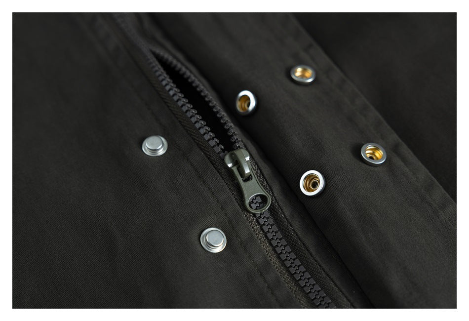 Close-up of a black zipper and surrounding silver and gold-tone snap fasteners.
