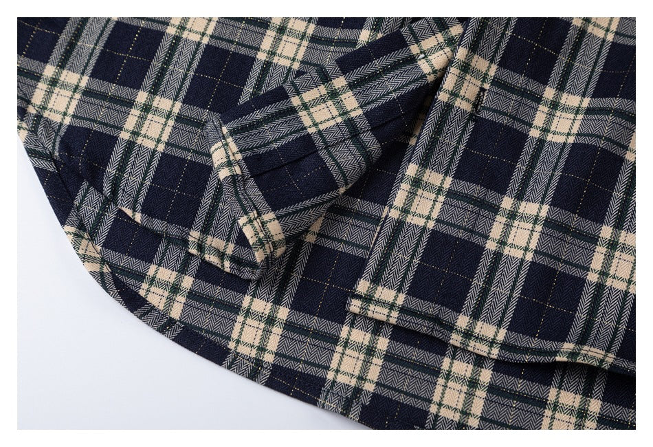 Close-up of the curved hem and a pocket on a navy, cream, and green plaid shirt.