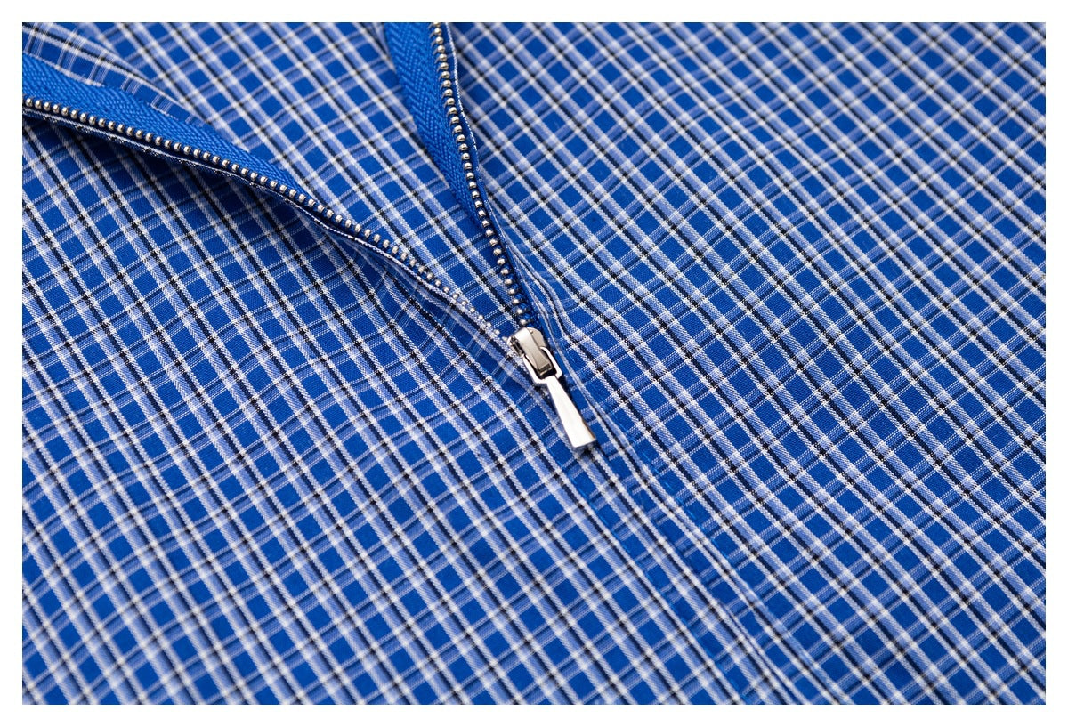 Close-up of a silver zipper on blue plaid fabric.