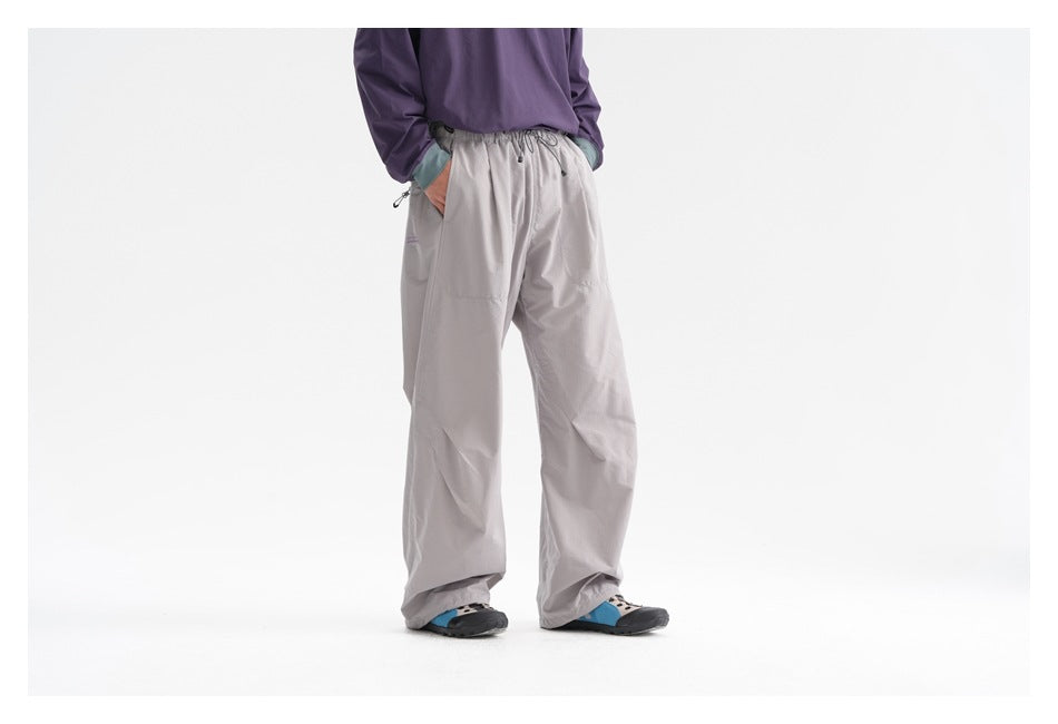 Model wearing loose light gray drawstring pants with a purple top, shown from waist to shoes.